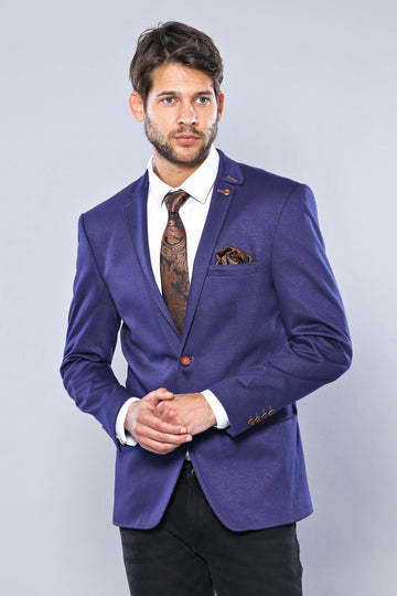 Man wearing a purple blazer with a white shirt and patterned tie on a light gray background