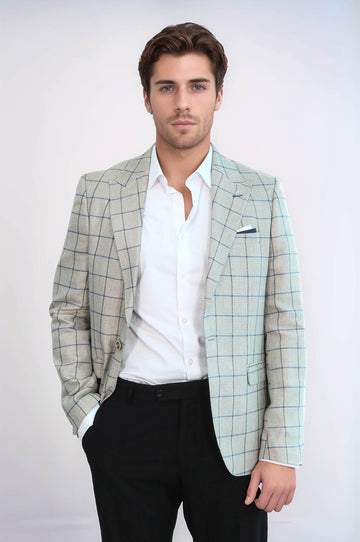 Man wearing a light green checkered blazer over a white shirt with black pants on a white background