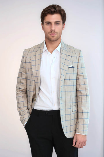 Man wearing a light-colored checkered blazer over a white shirt with black pants on a plain background