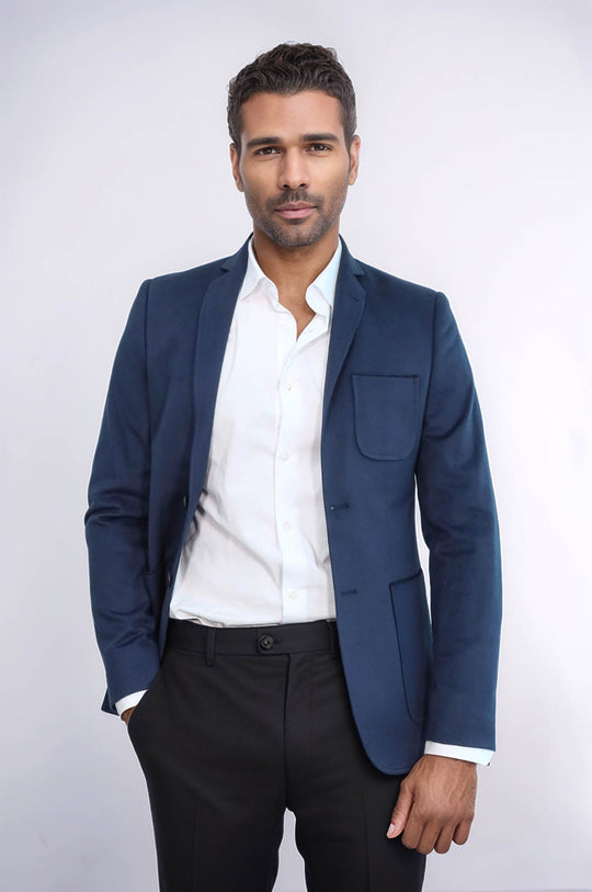 Man wearing a blue blazer over a white shirt and black pants on a white background