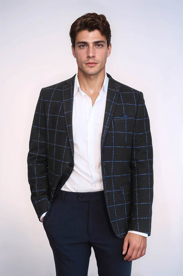 Man wearing a blue checkered blazer over a white shirt with a plain background