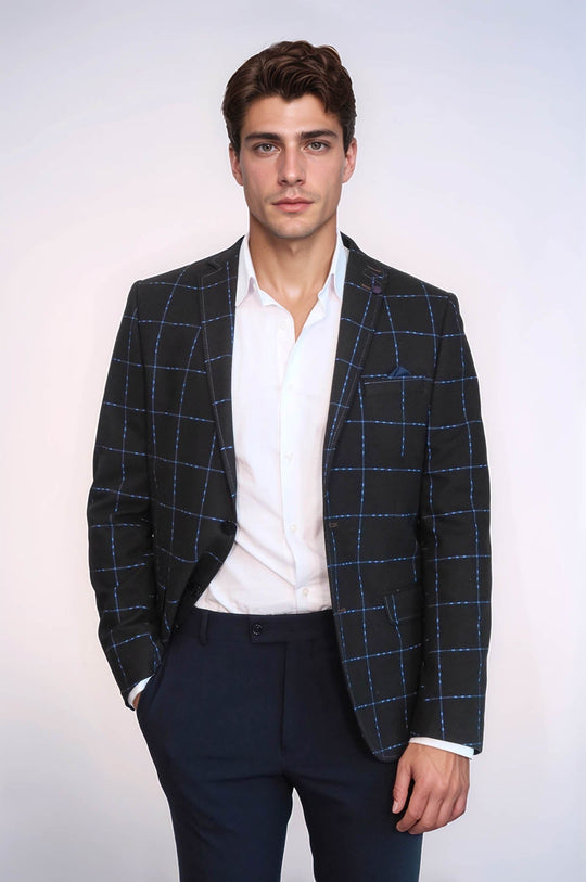 Man wearing a blue checkered blazer over a white shirt with a plain background