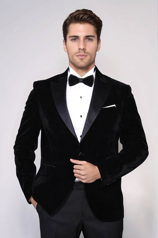 Man wearing a black velvet tuxedo with a white shirt and bow tie on a white background