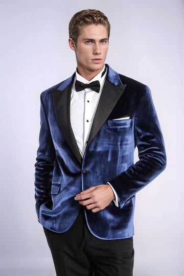 Man wearing a blue velvet tuxedo jacket with a white shirt and black bow tie on a white background