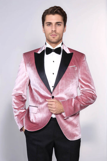 Man wearing a pink velvet tuxedo with black lapels on a white background