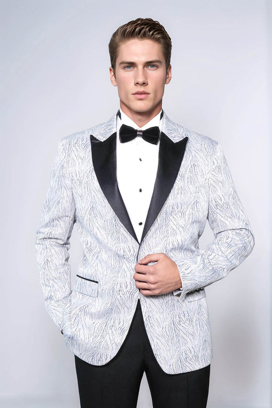 Man wearing a white patterned tuxedo with black lapels and bow tie on a light gray background