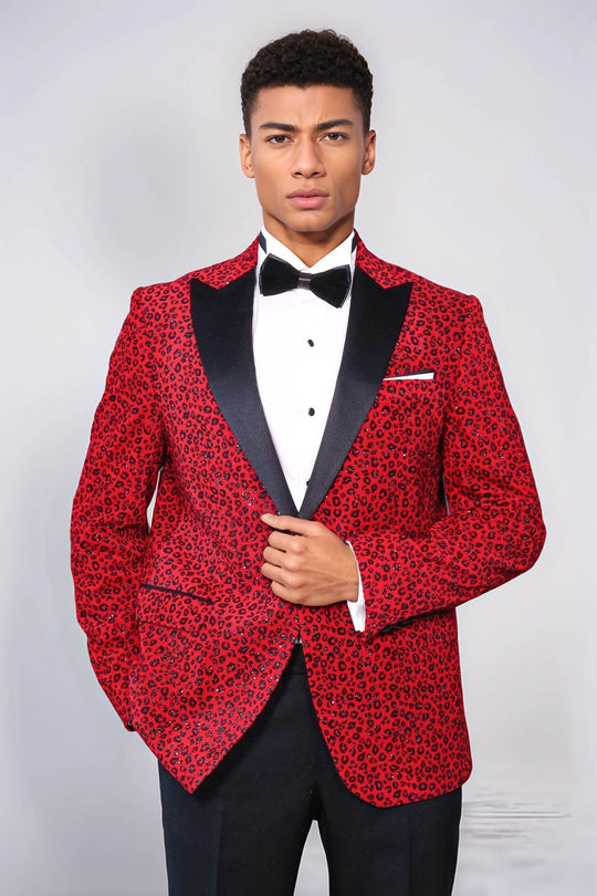 Man wearing a red patterned tuxedo with black lapels on a white background