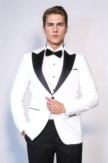 Man wearing a white tuxedo with black lapels and bow tie on a light gray background