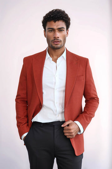 Man wearing a red blazer over a white shirt with black pants on a white background