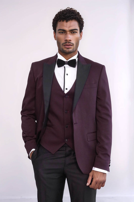 Man wearing a burgundy tuxedo with a white shirt and black bow tie on a plain background