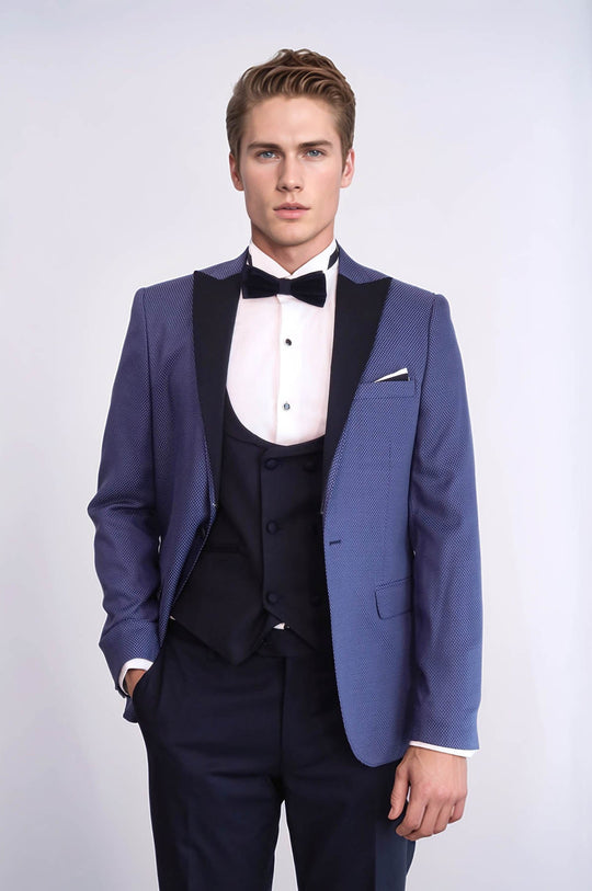 Man wearing a blue tuxedo with a white shirt and black bow tie on a light gray background