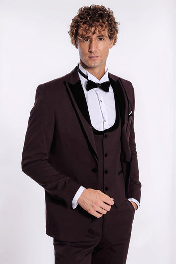Man wearing a formal brown tuxedo with a bow tie on a white background