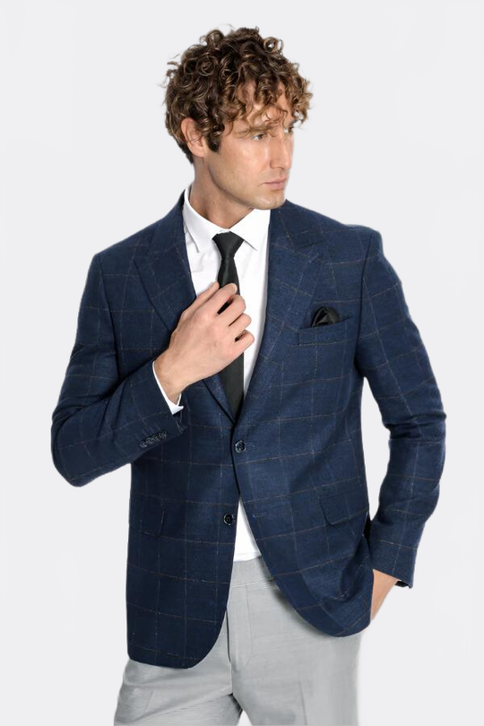 Man wearing a blue checkered blazer with a white shirt and gray pants on a light gray background