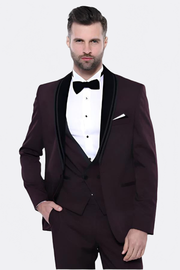 Man wearing a formal burgundy tuxedo with a white shirt and black bow tie on a light gray background