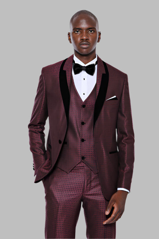 Man wearing a burgundy suit with black lapels and a bow tie on a gray background